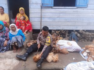 Membaur ke “Emak-emak”, Bhabinkamtibmas Polsek Padang Bolak Mengupas Kelapa