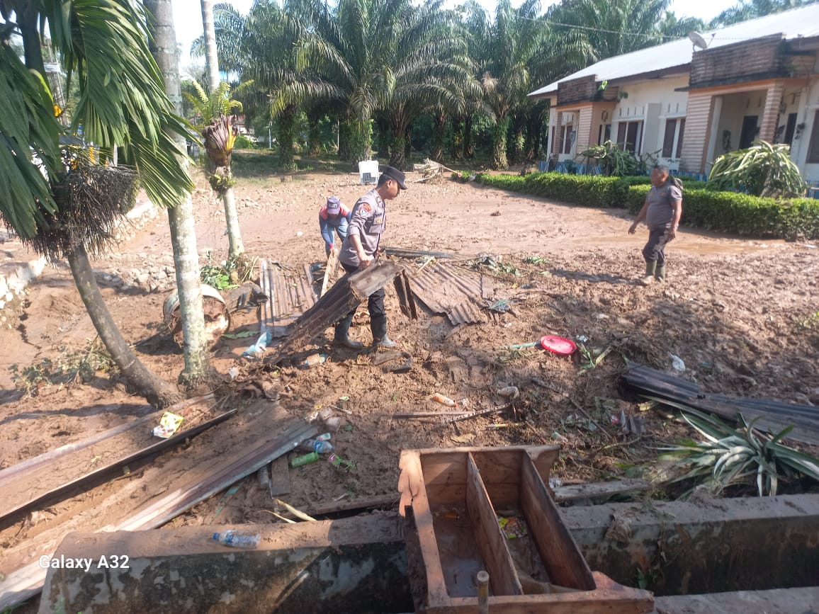 Personel Polsek Batang Toru bahu-memabahu bersama warga membersihkan material sisa banjir besar yang sempat melanda di lokasi itu