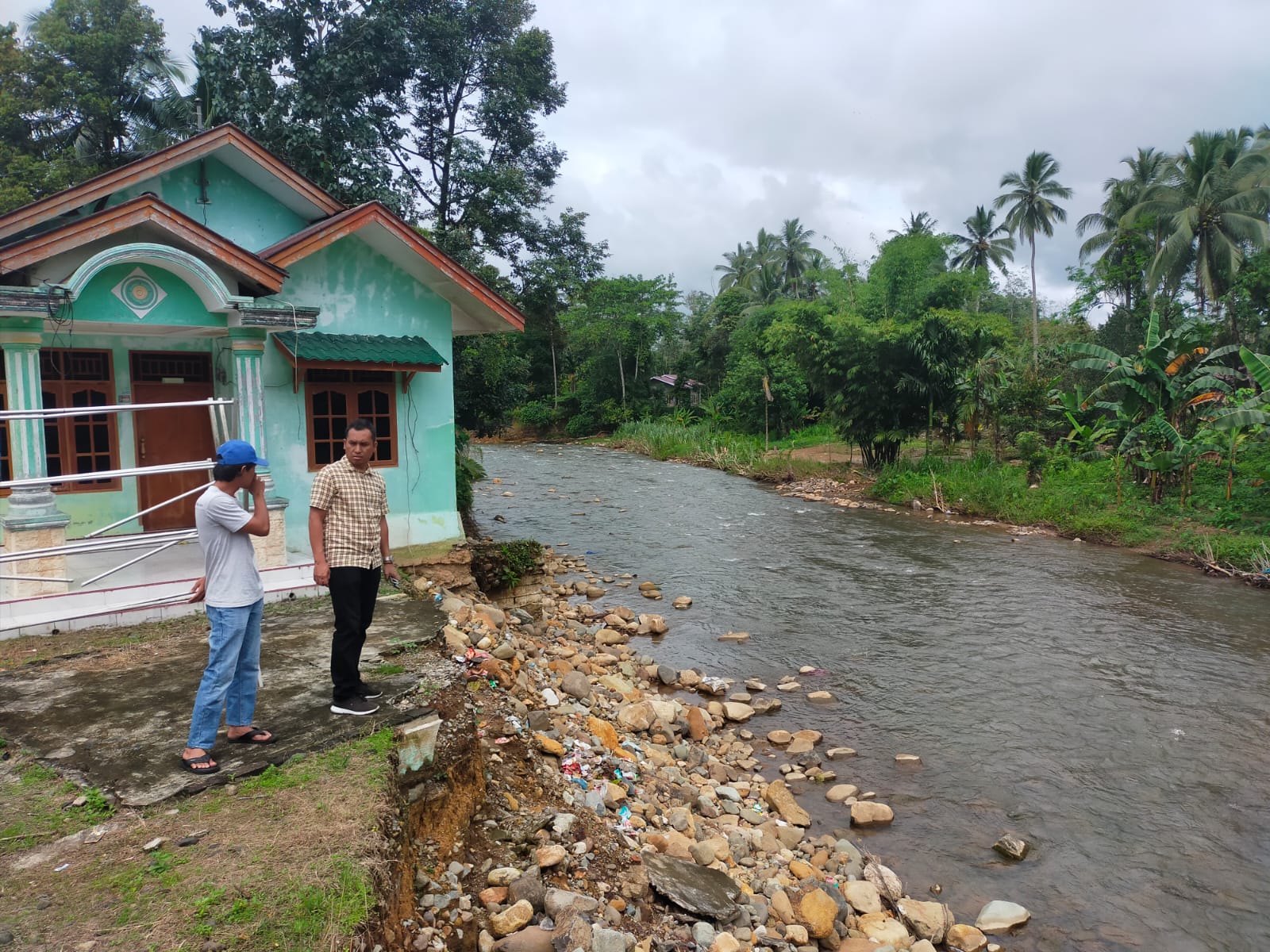 Kanit II Ekonomi Sat Reskrim Polres Tapsel, Ipda Ilham P Nasution, saat mengecek lokasi Rumah yang hanyut akibat tersapu arus Sungai yang besar saat banjir melanda di Desa Hapesong Lama, Kecamatan Batang Toru