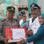 Kapolsek Padang Bolak, AKP Harun Manurung, menyerahkan bingkisan ke salah satu Kepala Desa karena meraih Juara III tertib administrasi saat HKG PKK ke-52 Kabupaten Paluta