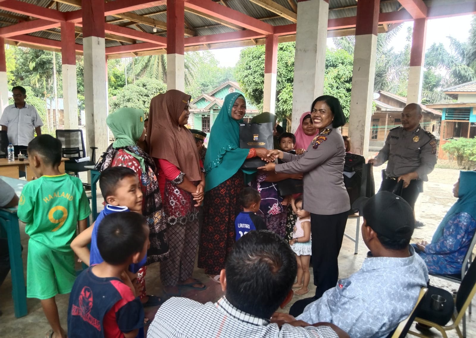 Kasi Humas, AKP Maria Marpaung, beri bingkisan ke salah satu masyarakat yang mengikuti program bertajuk gerakan Kapolres Tapsel Jelajah Huta di Desa Silangkitang, Kecamatan Aek Bilah