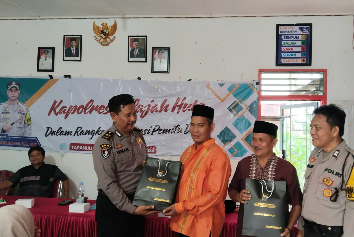 Ka SPKT Polres Tapsel, Ipda Irwan H Sarumpaet, menyerahkan souvenir ke perwakilan masyarakat di sela gerakan Kapolres Jelajah Huta