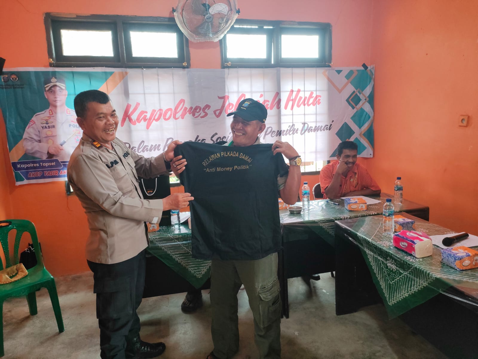 Kasat Tahti Polres Tapsel, Iptu Asjul Pane, menyerahkan kaos relawan Pilkada damai anti politik uang dalam gerakan Kapolres Jelajah Huta