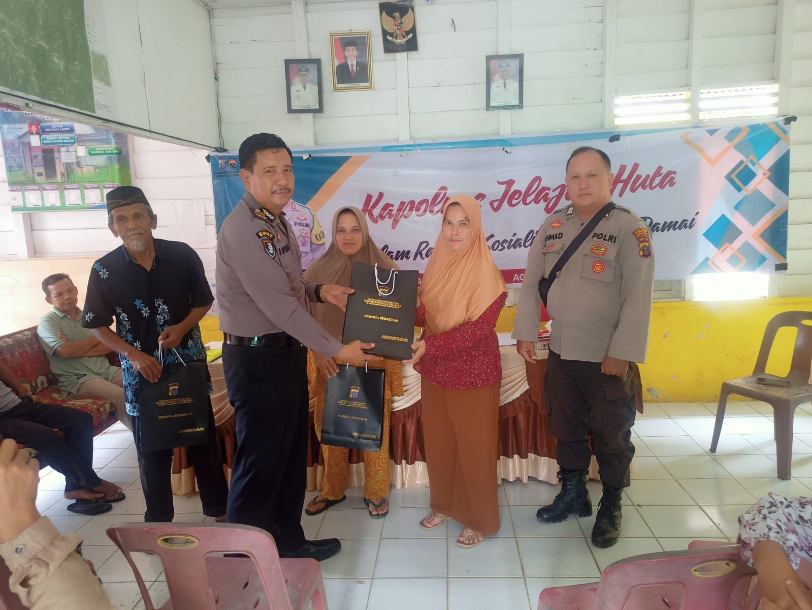 Ka SPKT Polres Tapsel, Ipda Irwan H Sarumpaet, menyerahkan souvenir ke perwakilan masyarakat di sela gerakan Kapolres Jelajah Huta
