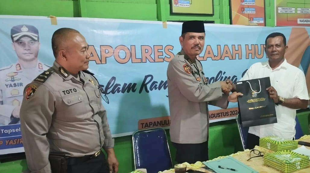 Kabag SDM Polres Tapsel, AKP Sumanto Naibaho, saat menyerahkan souvenir ke perwakilan masyarakat yang hadir dalam gerakan Kapolres Jelajah Huta