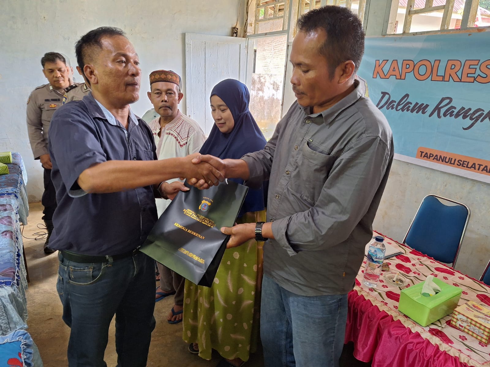 KBO Sat Resnarkoba Polres Tapsel, Ipda TP Saragih, saat menyerahkan souvenir ke perangkat Desa Siuhom di sela gerakan Kapolres Jelajah Huta