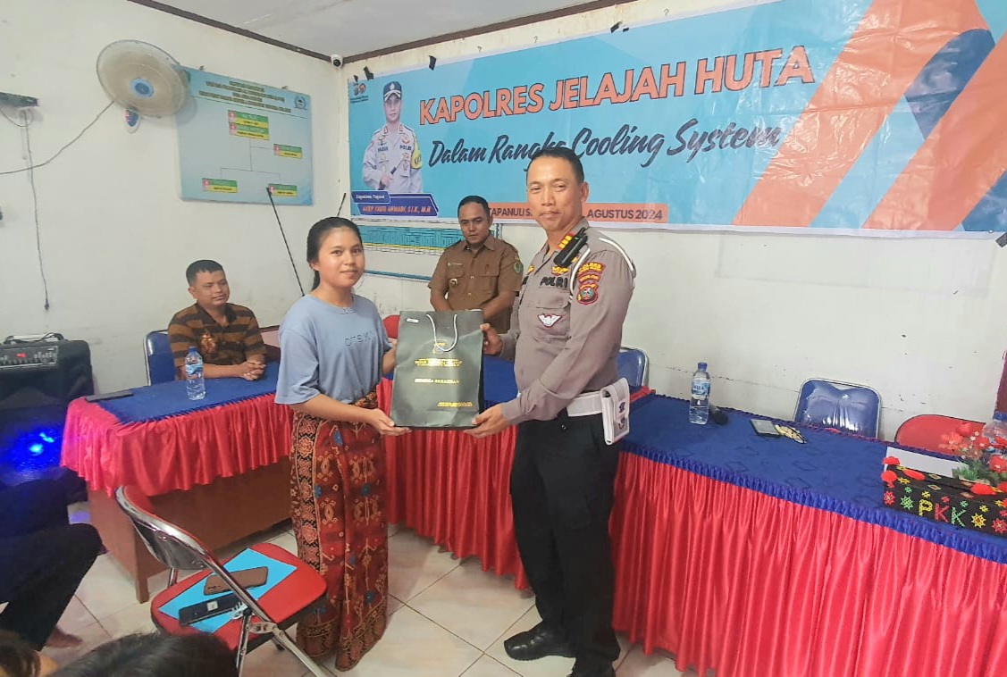 Kasat Lantas Polres Tapsel, AKP Danil Saragih, saat menyerahkan souvenir sebagai tanda untuk jadi pelopor tertib berlalulintas ke perwakilan masyarakat di sela gerakan Kapolres Jelajah Huta