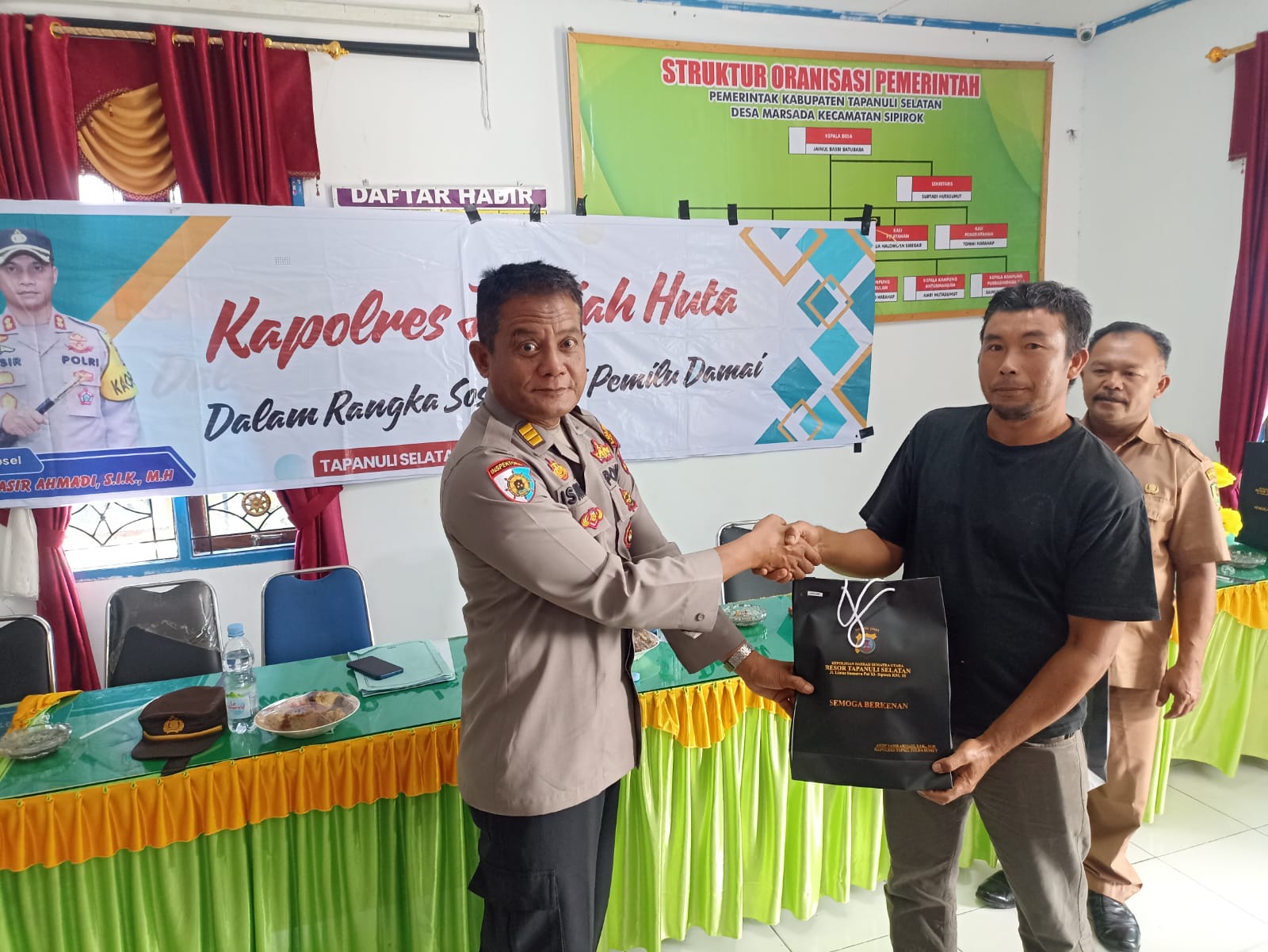 Kasiwas Polres Tapsel, AKP Ismaya, saat serahkan souvenir ke salah satu perwakilan masyarakat di sela gerakan Kapolres Jelajah Huta