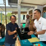 Kanit Tipiter Sat Reskrim Polres Tapsel, Ipda Ilham P Nasution, saat menyerahkan souvenir ke perwakilan masyarakat di sela gerakan Kapolres Jelajah Huta