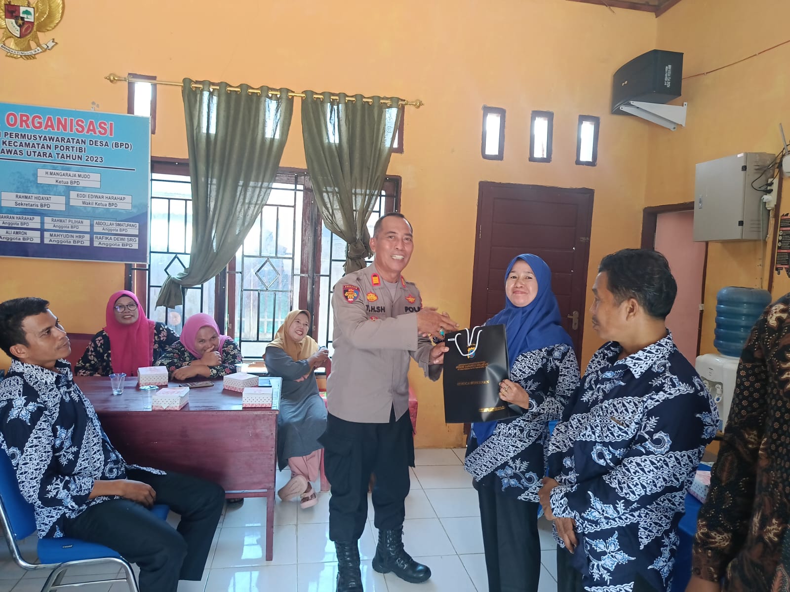 Kasi Propam Polres Tapsel, AKP R Trihardjanto, saat menyerahkan souvenir ke perwakilan masyarakat di sela gerakan Kapolres Jelajah Huta