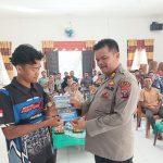 Kasikum Polres Tapsel, AKP Victor Sihombing, memberi stiker bahaya narkoba dan KDRT ke salah satu masyarakat yang hadiri gerakan Kapolres Jelajah Huta di Kabupaten Paluta