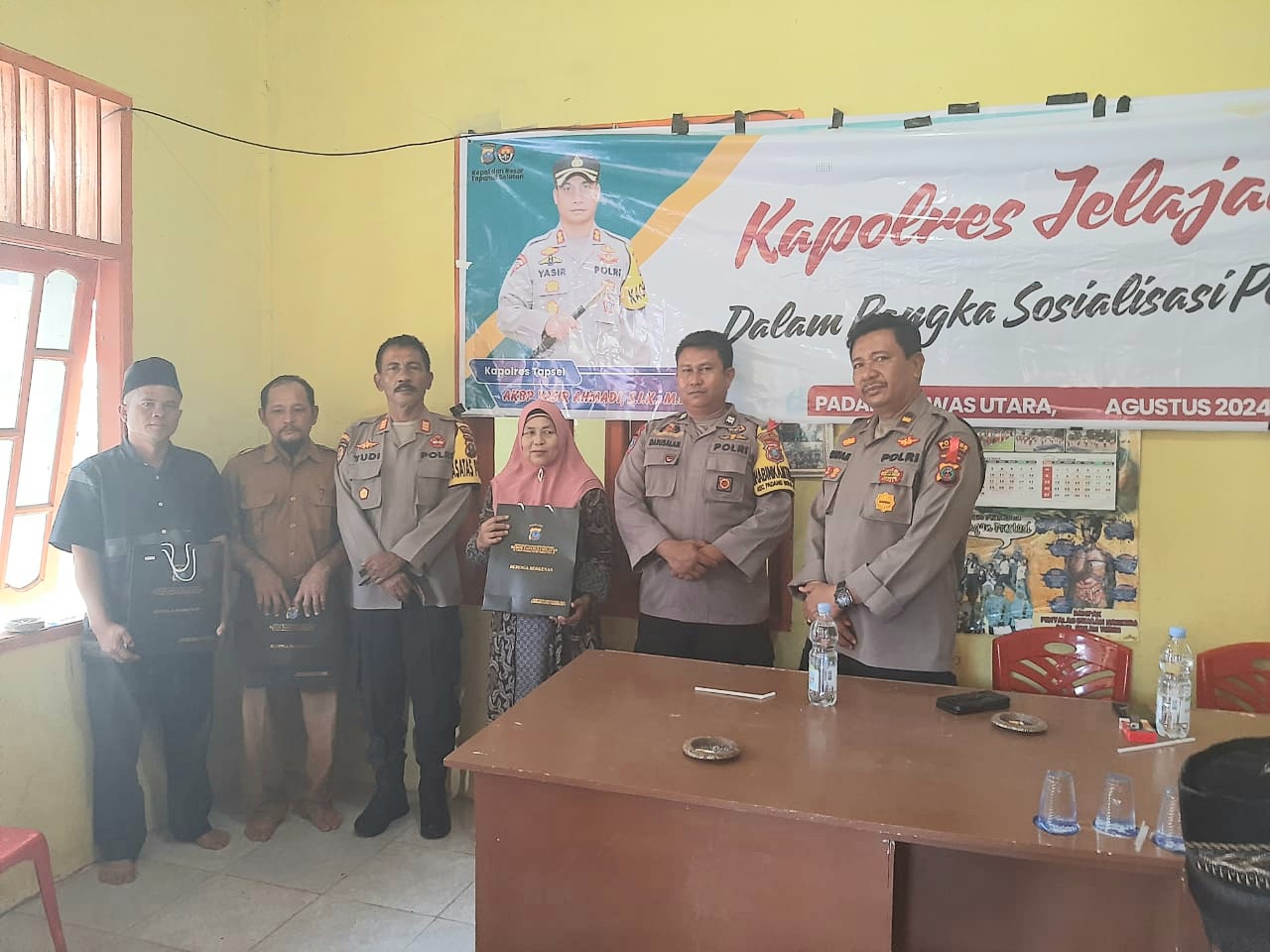 Kasat Binmas Polres Tapsel, AKP Eka Wahyudi, didampingi Ka SPKT, Ipda Irwan H Sarumpaet, usai menyerahkan souvenir ke perwakilan masyarakat di sela gerakan Kapolres Jelajah Huta
