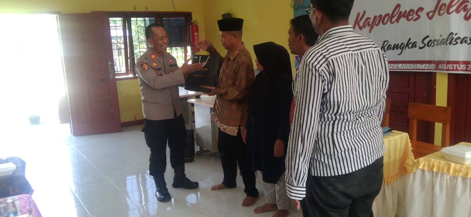 Kasi Propam Polres Tapsel, AKP R Trihardjanto, saat menyerahkan souvenir ke perwakilan masyarakat di sela gerakan Kapolres Jelajah Huta
