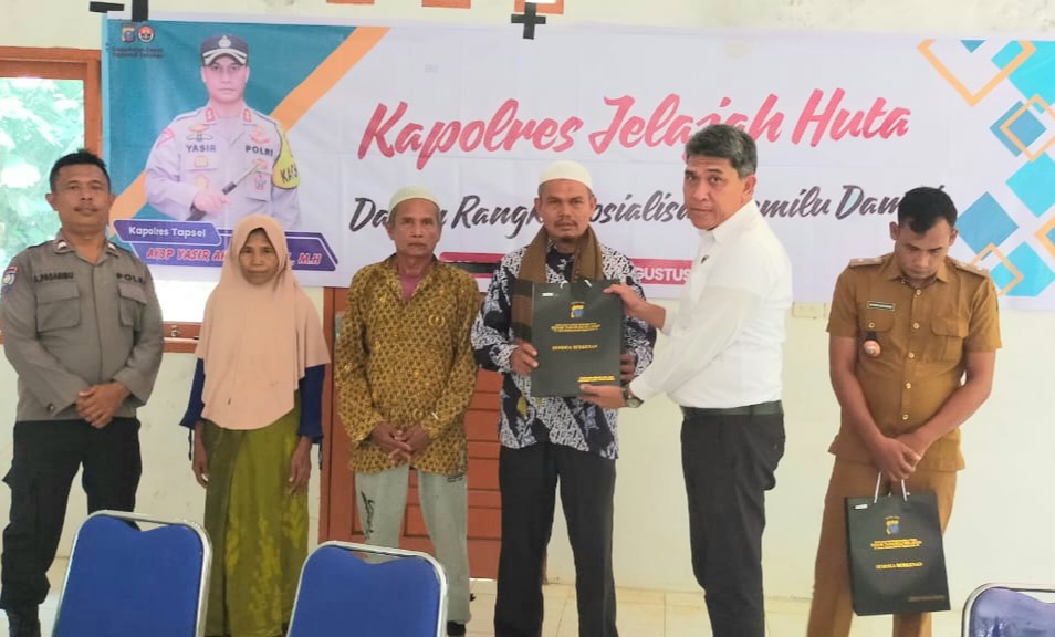 KBO Sat Reskrim Polres Tapsel, Iptu Aswin Manurung, saat menyerahkan souvenir kepada perwakilan masyarakat di sela gerakan Kapolres Jelajah Huta