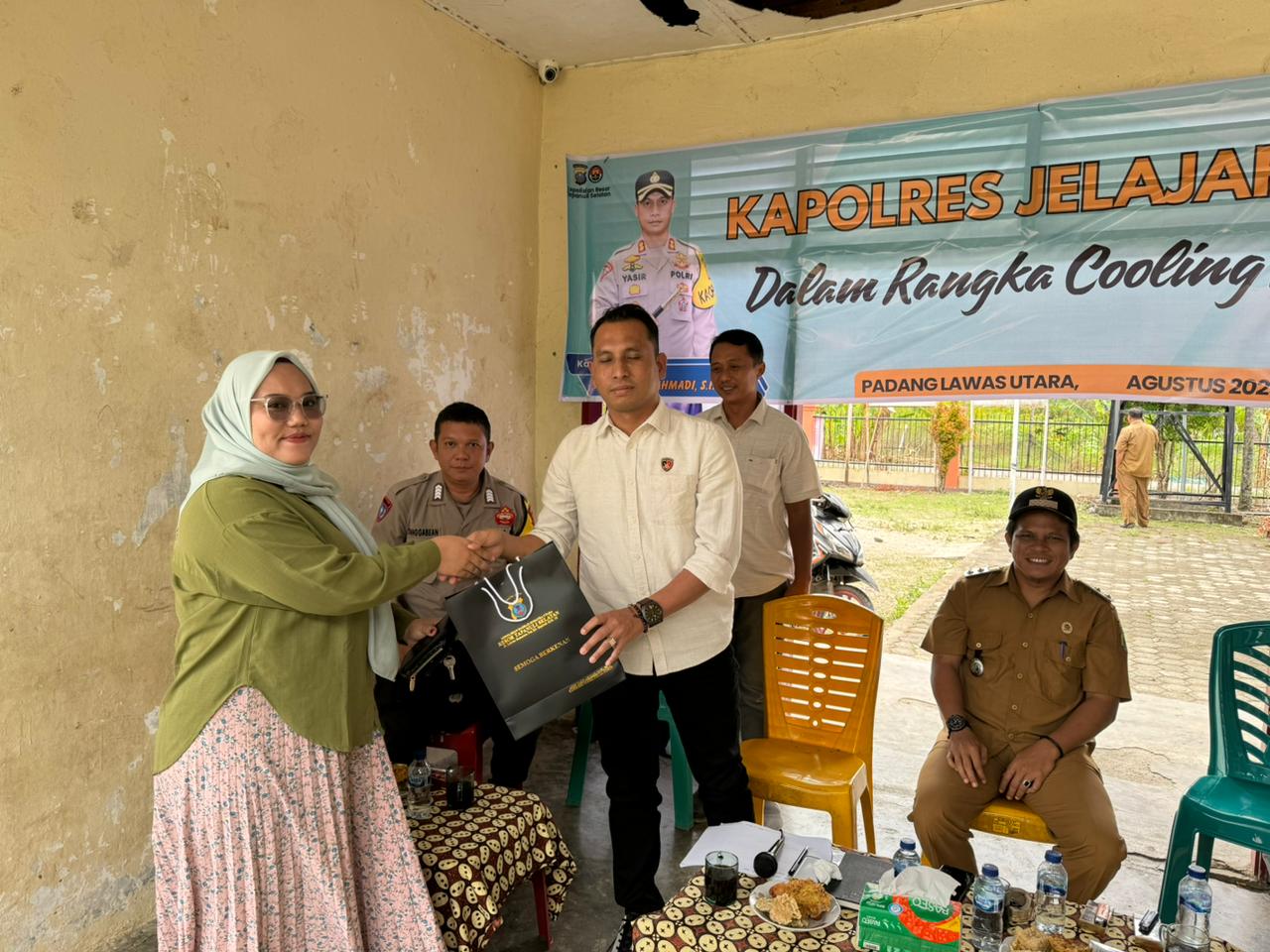 Kanit Tipiter Sat Reskrim Polres Tapsel, Ipda Ilham P Nasution, saat serahkan souvenir ke salah satu perwakilan masyarakat di sela gerakan Kapolres Jelajah Huta