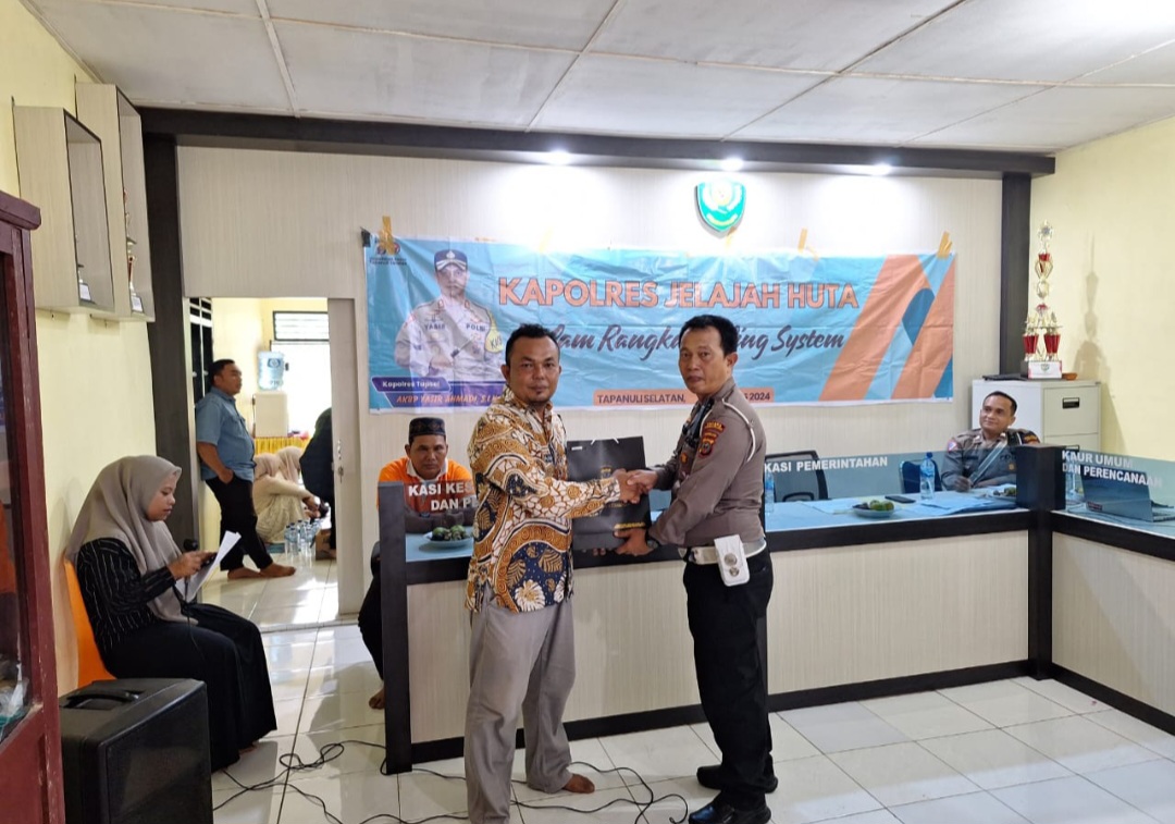 KBO Sat Lantas Polres Tapsel, Ipda Hary Agus Pohan, menyerahkan souvenir ke perwakilan masyarakat di sela gerakan Kapolres Jelajah Huta