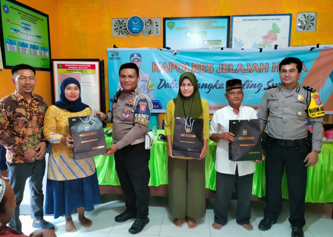 Kanit Gakkum Sat Lantas Polres Tapsel, Ipda Samuel Jefri Hutapea, saat menyerahkan souvenir ke perwakilan masyarakat di sela gerakan Kapolres Jelajah Huta