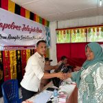 Kanit Tipiter Sat Reskrim Polres Tapsel, Ipda Ilham P Nasution, saat menyerahkan souvenir ke perwakilan masyarakat di sela gerakan Kapolres Tapsel Jelajah Huta di Kabupaten Paluta