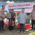 Kasi Propam Polres Tapsel, AKP R Triharjanto, saat menyerahkan souvenir ke perwakilan masyarakat di sela gerakan Kapolres Jelajah Huta di Kabupaten Paluta