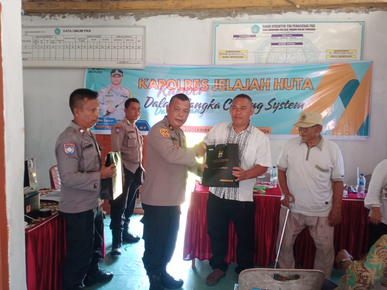 Kabag Log Polres Tapsel, Kompol Daulat MZ Harahap, saat menyerahkan spuvenir kepada perwakilan masyarakat di sela gerakan Kapolres Jelajah Huta di Kabupaten Paluta