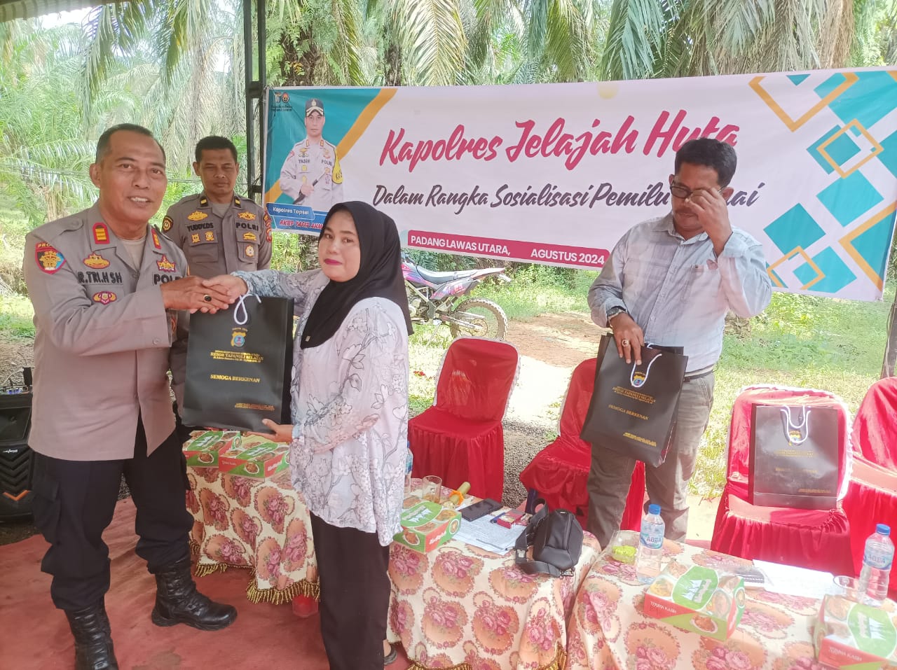 Kasi Propam Polres Tapsel, AKP R Triharjanto, menyerahkan souvenir ke perwakilan masyarakat di sela gerakan Kapolres Jelajah Huta