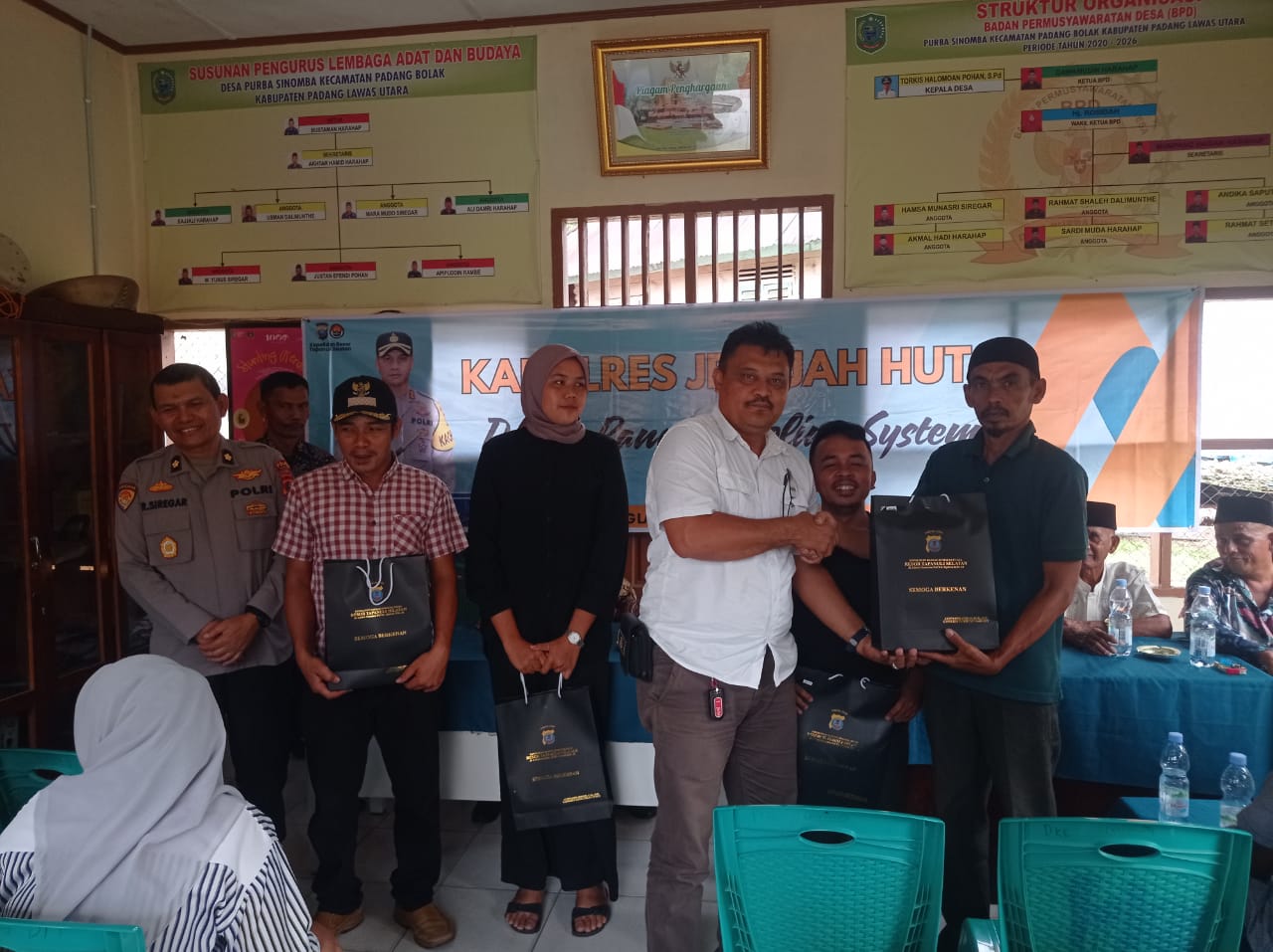Kanit I Pidum Sat Reskrim Polres Tapsel, Ipda Maraden Hutabarat, bersama Kabag Ren, Kompol Rudi Siregar, menyerahkan souvenir ke perwakilan masyarakat yang hadir dalam gerakan Kapolres Jelajah Huta