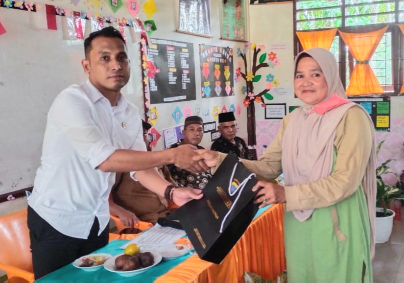 Kanit Tipiter Sat Reskrim Polres Tapsel, Ipda Ilham P Nasution, saat menyerahkan souvenir ke masyarakat di sela gerakan Kapolres Jelajah Huta