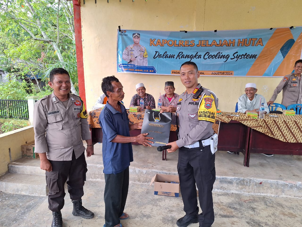 Kasat Lantas Polres Tapsel, AKP Danil Saragih, saat menyerahkan souvenir ke perwakilan masyarakat di sela gerakan Kapolres Tapsel Jelajah Huta
