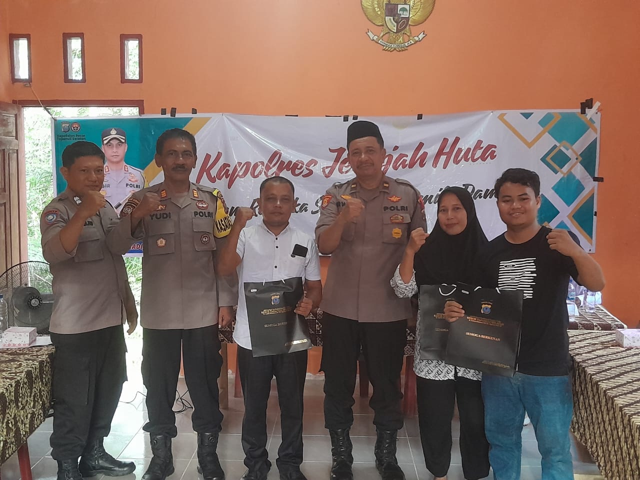 Kasat Binmas Polres Tapsel, AKP Eka Wahyudi, didampingi Ka SPKT, Ipda Irwan Sarumpaet, usai menyerahkan souvenir ke perwakilan masyarakat di sela gerakan Kapolres Jelajah Huta di Kabupaten Paluta