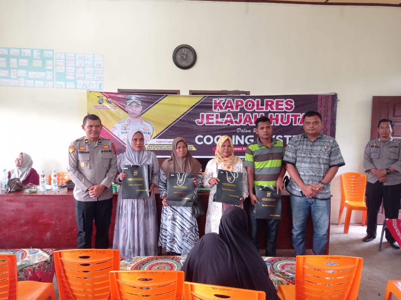 Kanit I Pidum Sat Reskrim Polres Tapsel, Ipda Maraden Hutabarat, bersama Kabag Ren, Kompol Rudi Siregar, menyerahkan souvenir ke perwakilan masyarakat yang hadir dalam gerakan Kapolres Jelajah Huta
