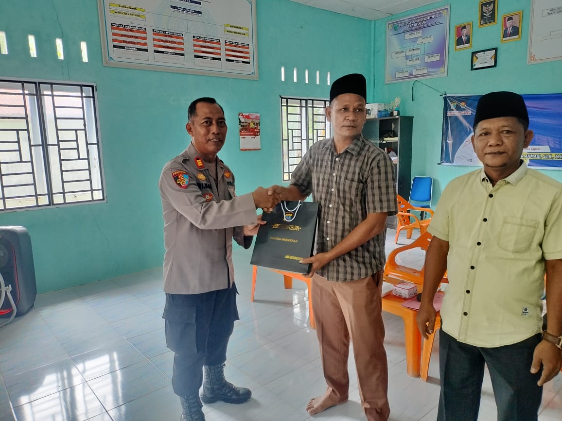 Kasi Propam Polres Tapsel, AKP R Triharjanto, saat menyerahkan souvenir ke perwakilan masyarakat di sela gerakan Kapolres Jelajah Huta
