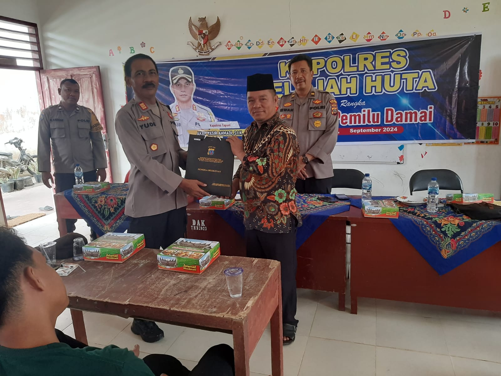 Kasat Binmas Polres Tapsel, AKP Eka Wahyudi, didampingi Ka SPKT, Ipda Irwan Sarumpaet, saat menyerahkan souvenir ke perwakilan perangkat Desa Aek Simanat yang hadir dalam gerakan Kapolres Jelajah Huta
