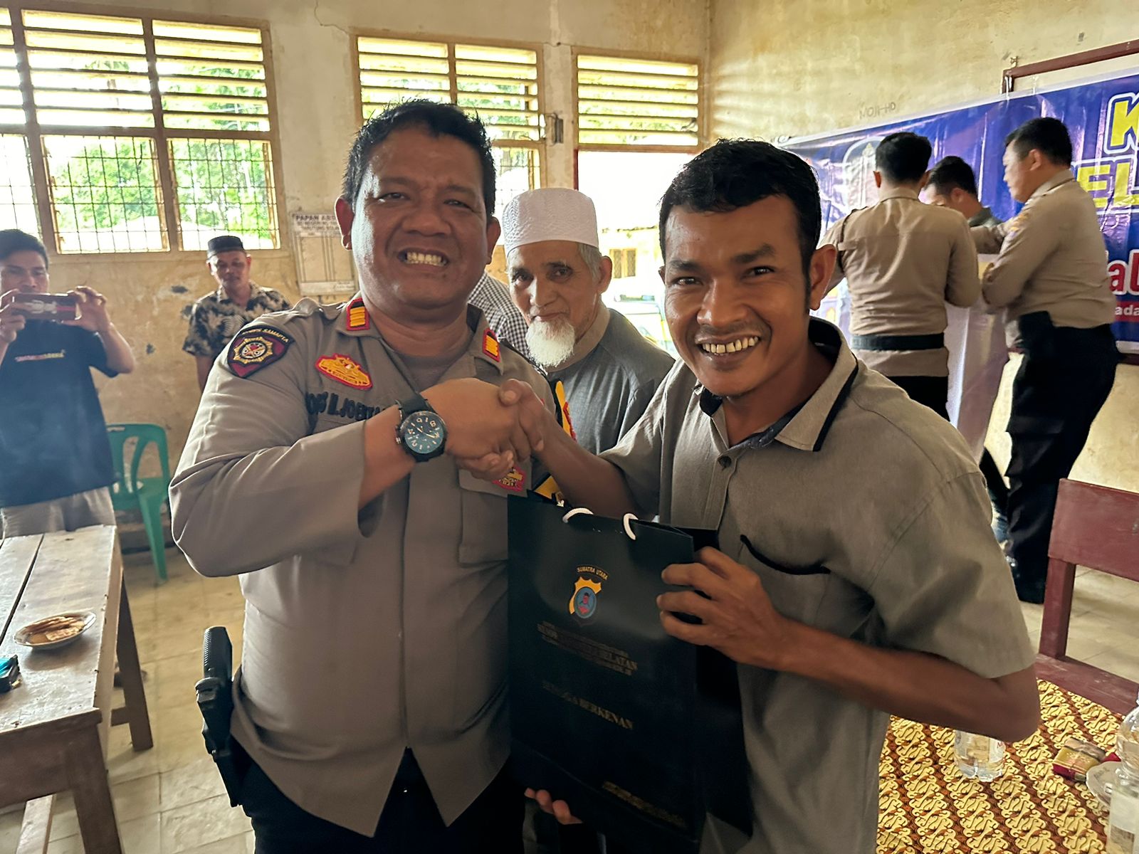 Kasat Samapta Polres Tapsel, AKP Tona Simanjuntak, saat menyerahkan souvenir ke perwakilan masyarakat di sela gerakan Kapolres Jelajah Huta