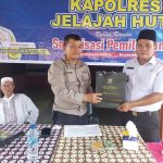 Kasat Tahti Polres Tapsel, Iptu Asjul Pane, saat menyerahkan souvenir ke perangkat Desa dan perwakilan masyarakat di sela gerakan Kapolres Jelajah Huta