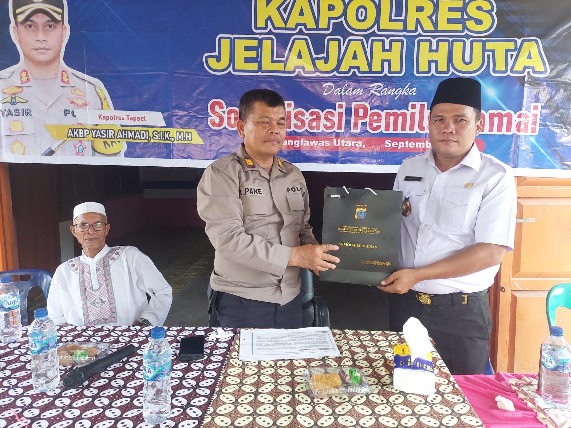 Kasat Tahti Polres Tapsel, Iptu Asjul Pane, saat menyerahkan souvenir ke perangkat Desa dan perwakilan masyarakat di sela gerakan Kapolres Jelajah Huta