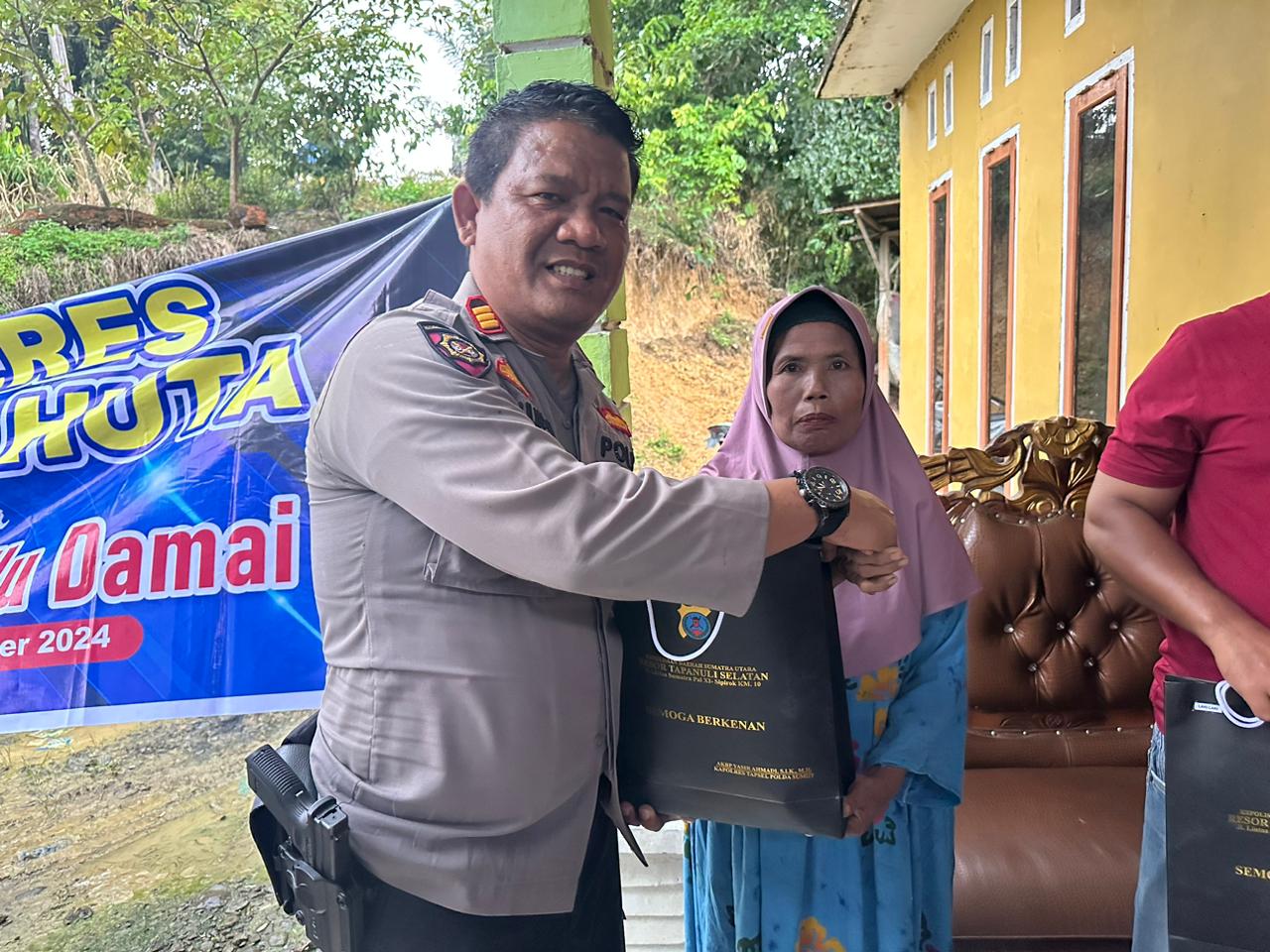 Kasat Samapta Polres Tapsel, AKP Tona Simanjuntak, saat menyerahkan souvenir ke perwakilan masyarakat di sela gerakan Kapolres Jelajah Huta