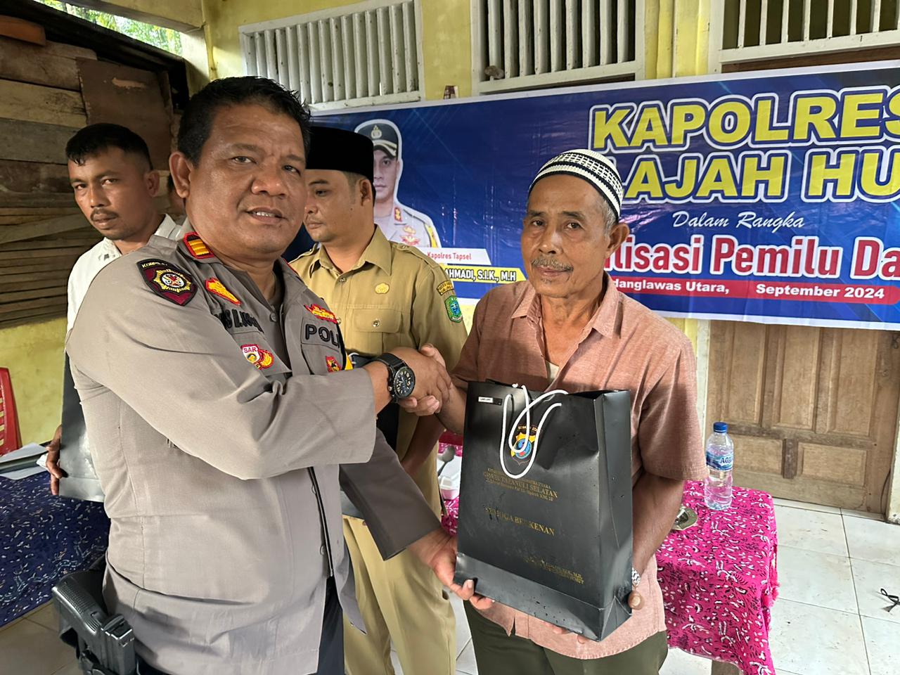 Kasat Samapta Polres Tapsel, AKP Tona Simanjuntak, saat menyerahkan souvenir ke perwakilan masyarakat di sela gerakan Kapolres Jelajah Huta