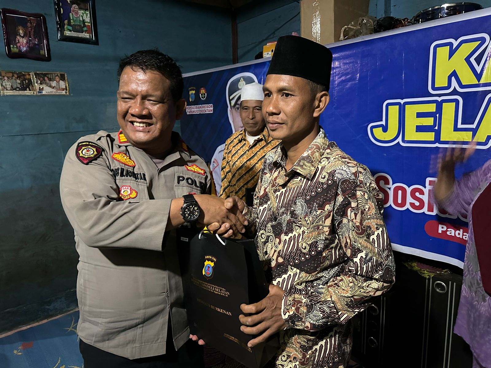Kasat Samapta Polres Tapsel, AKP Tona Simanjuntak, saat menyerahkan souvenir ke perwakilan masyarakat di sela gerakan Kapolres Jelajah Huta