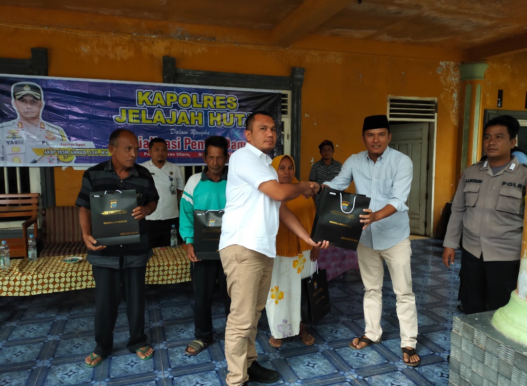 Kasat Intelkam Polres Tapsel, Iptu Oloan Lubis, saat menyerahkan souvenir ke perwakilan masyarakat di sela gerakan Kapolres Jelajah Huta