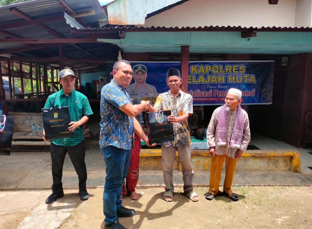 Kasat Intelkam Polres Tapsel, Iptu Oloan Lubis, saat menyerahkan souvenir ke perwakilan masyarakat di sela gerakan Kapolres Tapsel Jelajah Huta