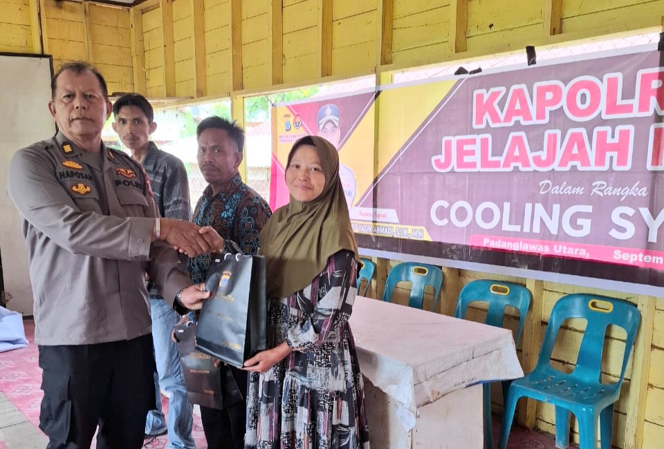 Kabag Log Polres Tapsel, AKP Haposan Harahap, saat menyerahkan souvenir ke perwakilan masyarakat di sela gerakan Kapolres Jelajah Huta