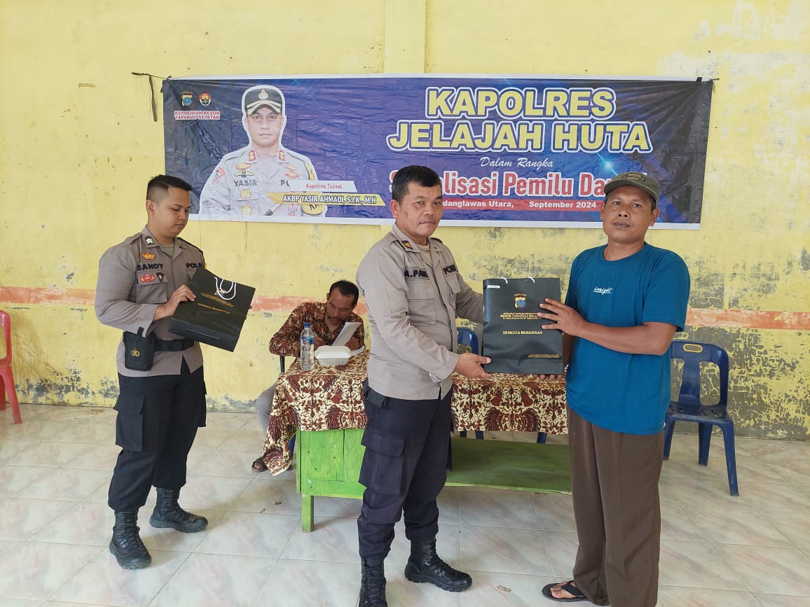 Kasat Tahti Polres Tapsel, Iptu Asjul Pane, menyerahkan souvenir ke perwakilan masyarakat yang hadir dalam gerakan Kapolres Jelajah Huta