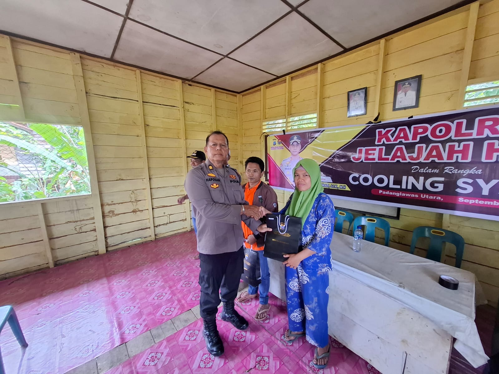 Kabag Log Polres Tapsel, AKP Haposan Harahap, saat menyerahkan souvenir ke perwakilan masyarakat di sela gerakan Kapolres Tapsel Jelajah Huta