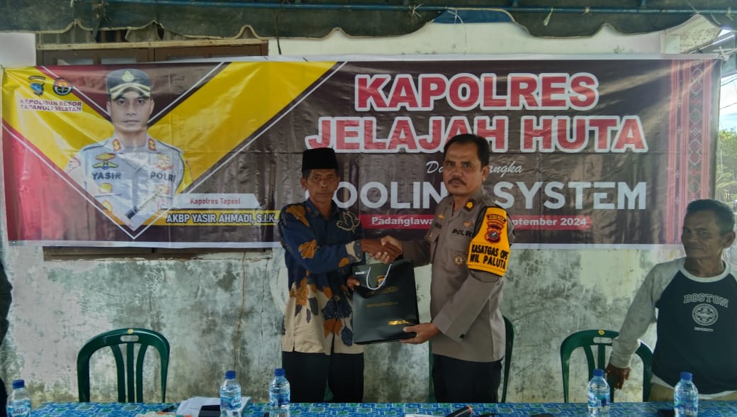 Kabag SDM Polres Tapsel, Kompol Sumanto Naibaho, saat menyerahkan souvenir kepada perwakilan masyarakat di sela gerakan Kapolres Jelajah Huta di Kabupaten Padang Lawas Utara