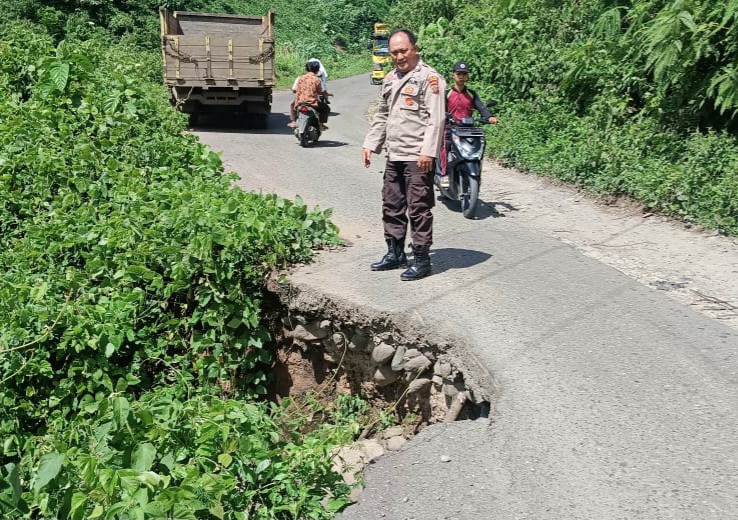Bhabinkamtibmas Polsek Batang Angkola, Aiptu Ahmad Ridoan Nasution, saat meninjau salah satu titik Jalan Lintas yang terancam longsor di Angkola Selatan, Kabupaten Tapsel