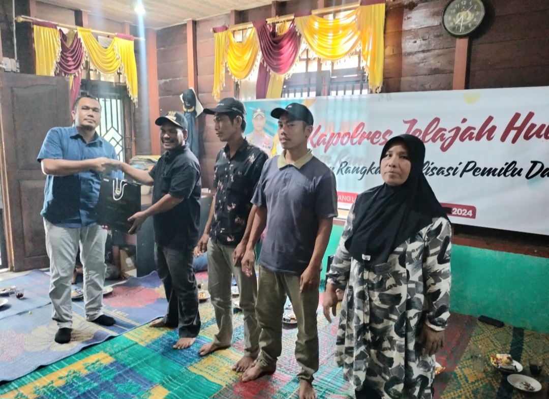 Kasat Intelkam Polres Tapsel, Iptu Oloan Lubis, saat menyerahkan souvenir ke masyarakat di sela gerakan Kapolres Jelajah Huta