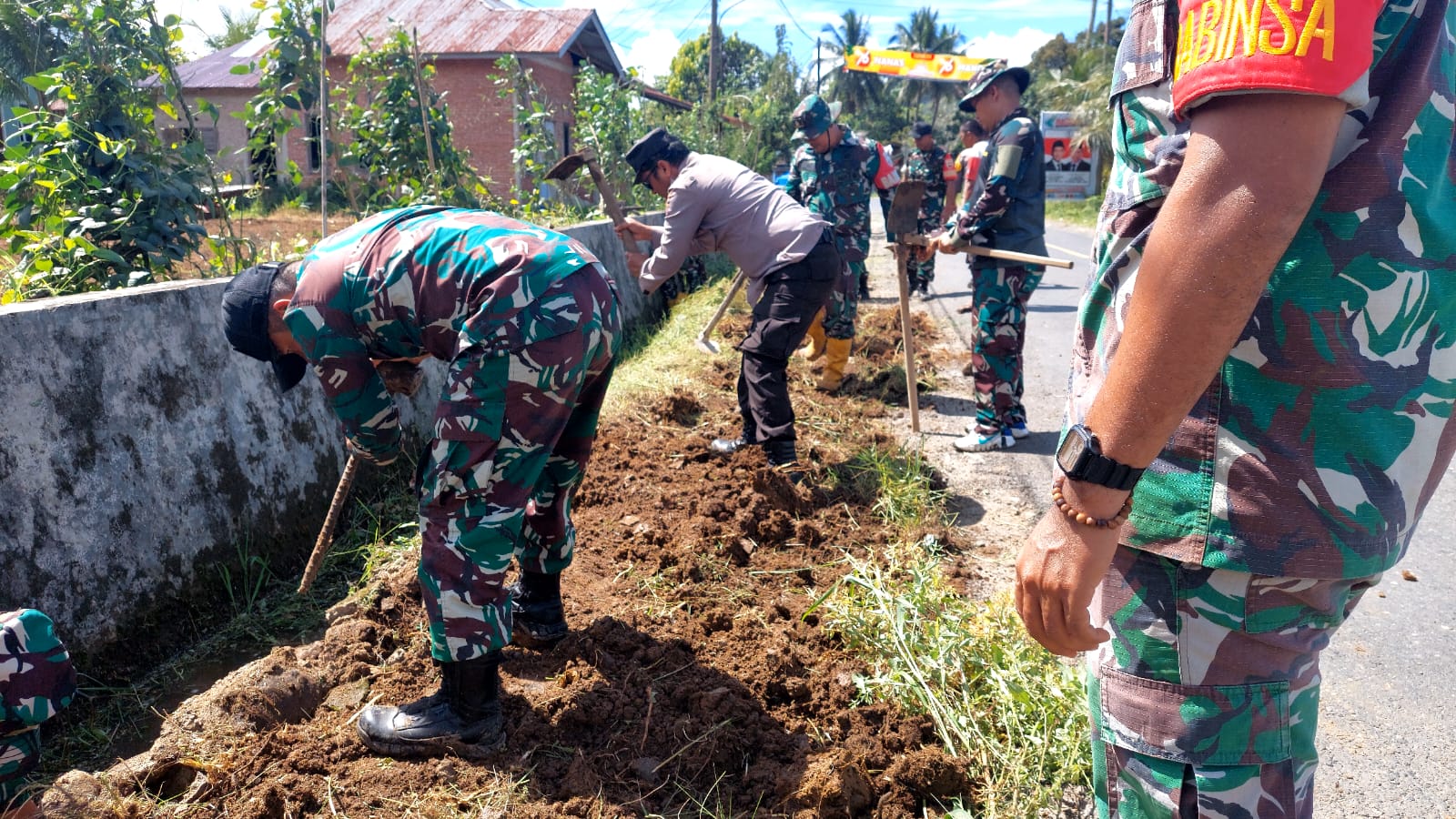 Personel Koramil dan Polsek Batang Toru saat menggelar kurve bersama dengan bergotongroyong membersihkan sisi kiri dan kanan Jalan Lintas di Desa Huta Baru Siagian