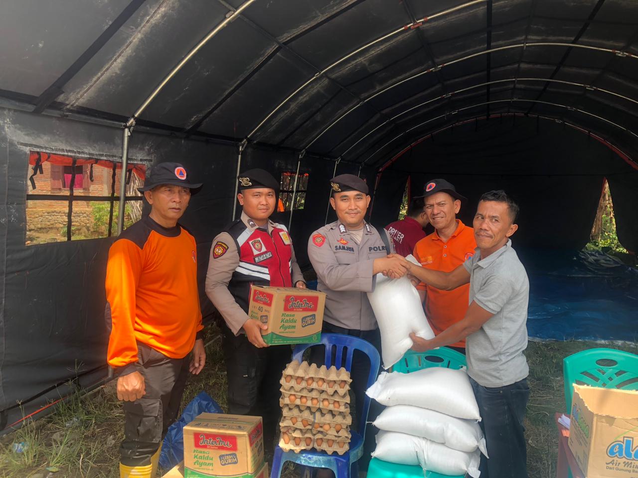 Personel Sat Samapta saat menyerahkan bantuan berupa sembako ke masyarakat yang terdampak banjir bandang di Desa Sipange Siunjam