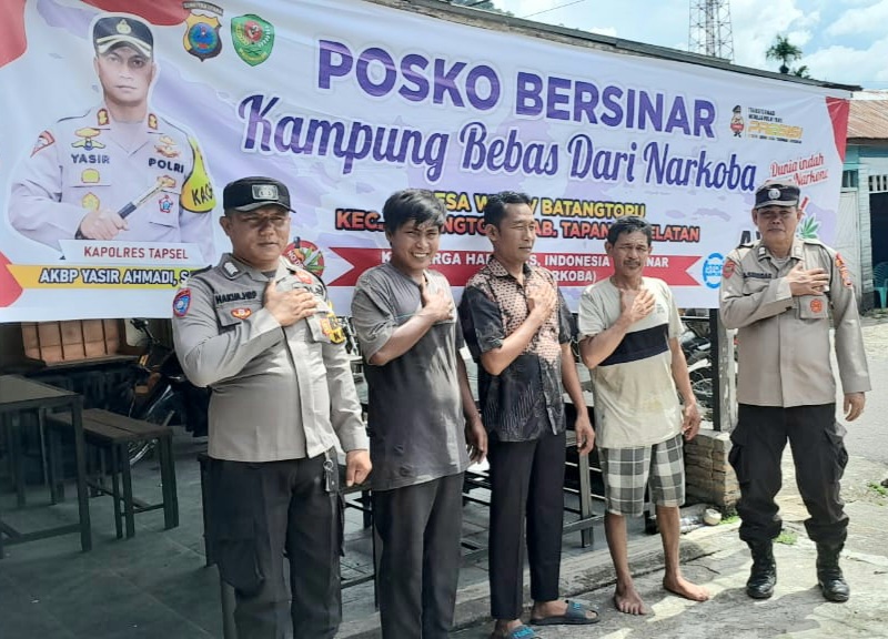 Bhabinkamtibmas Polsek Batang Toru, Bripka M Hakim Harahap, dan rekannya, usai memasang spanduk di Posko Kampung Bersinar