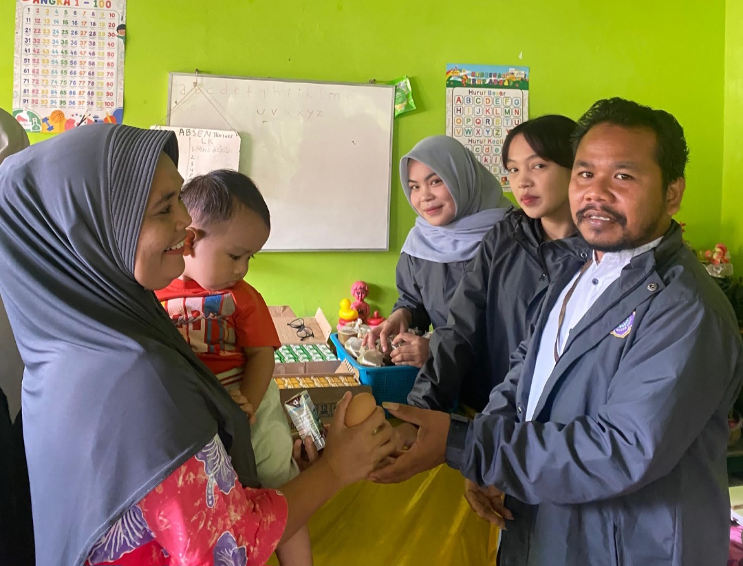 Ketua Kelompok KKN Mahasiswa UMTS, Syahminan Rambe, atau karib disapa Bung Rambe, saat menyerahkan makanan bergizi tambahan ke bayi di sela sosialisasi pencegahan Stunting